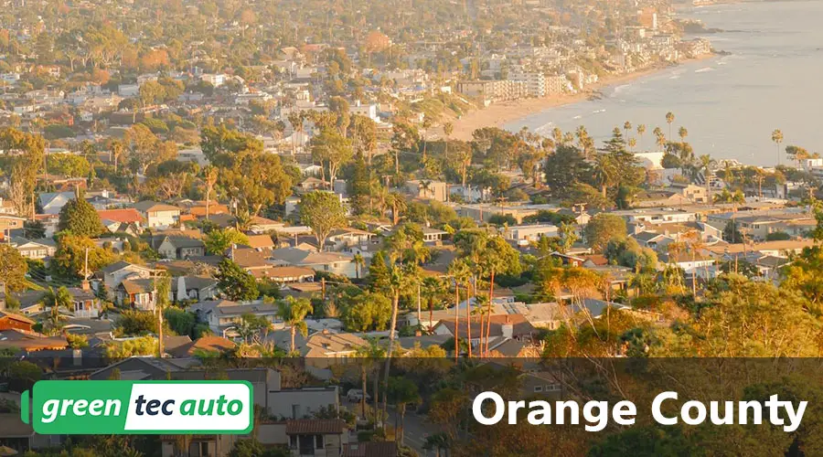 Aerial view of a coastal Orange County neighborhood with palm trees and houses along the shoreline, overlaid with ‘Orange County’ and a green logo banner.