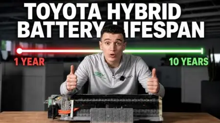 Man in a light gray pullover sits at a table with a hybrid battery module, giving two thumbs up as a red-to-green lifespan bar runs across the background labeled '1 YEAR' to '10 YEARS' and a bold 'TOYOTA HYBRID BATTERY LIFESPAN' headline above.
