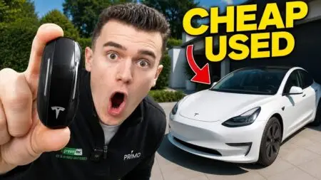 Man holds a Tesla key fob up to the camera beside a white Tesla in a driveway, with bold 'CHEAP USED' text overlay, suggesting a used-car video.